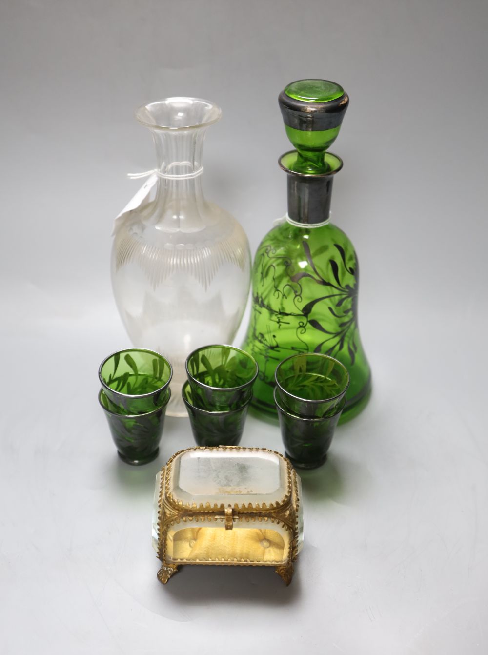 A 19th century French gilt-metal-mounted glass jewellery casket, a Venetian green glass liqueur set and a glass carafe,